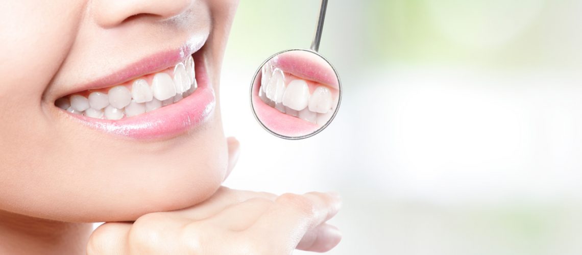 Healthy woman teeth and a dentist mouth mirror with nature green background, asian beauty